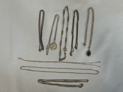 de nombreux bijoux en argent posés sur un tissu blanc