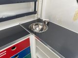 a sink in the corner of a kitchen with a mirror on the wall