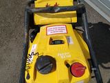 a yellow lawn mower sitting on the ground next to a garage