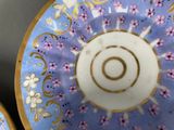a blue plate with a gold rim and a pink and white plate with flowers on it