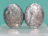 two silver coins sitting on top of each other on top of a table