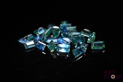 green and blue crystals are scattered on a black surface