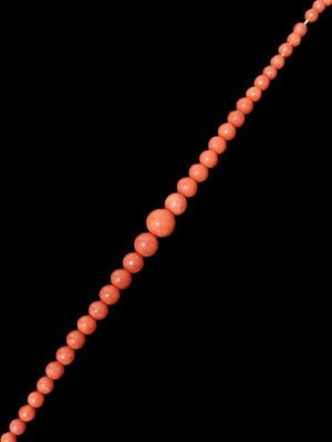 un gros plan d'un collier composé de perles de corail sur fond noir