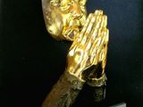 statue of a praying man with hands folded over his face