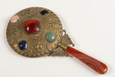 a small mirror with a red handle on a white surface