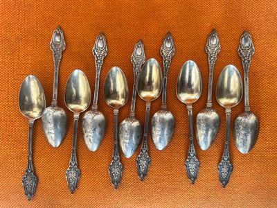six silver spoons are lined up in a row on an orange cloth