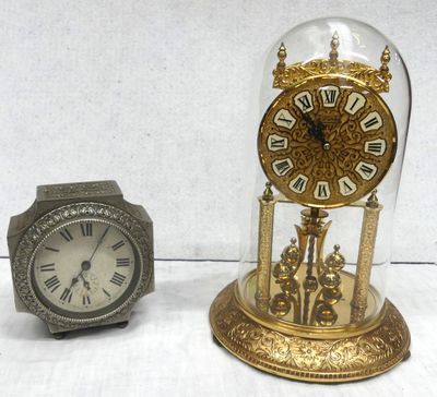 two clocks sitting next to each other under a glass dome