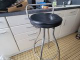 a black stool sitting in a kitchen next to a counter