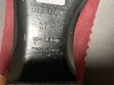the bottom of a pair of black leather shoes on a red surface