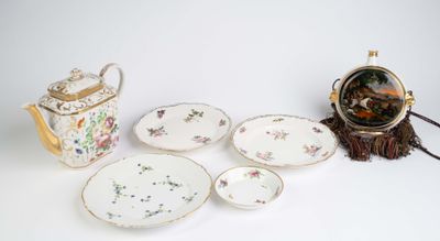 a table with a tea pot, tea pot, plates, and a clock