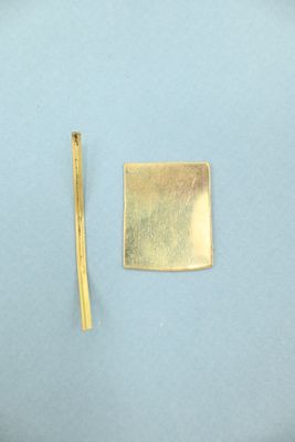 a piece of gold on a blue surface next to a piece of gold