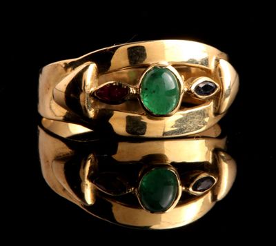 un gros plan d'une bague en or sertie de pierres vertes et rouges