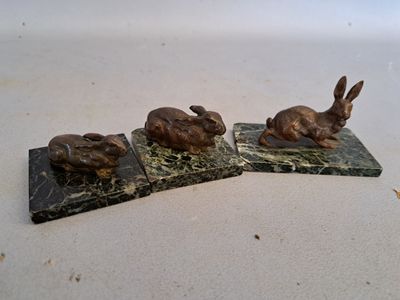 three statues of rabbits sitting on top of a marble block
