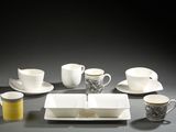 several cups and saucers are arranged on a table with a black background