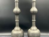 pair of antique pewed pewed metal vases on a gray background