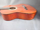 an orange acoustic guitar sitting on top of a white sheet
