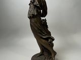 an antique bronze statue of a woman holding a bird