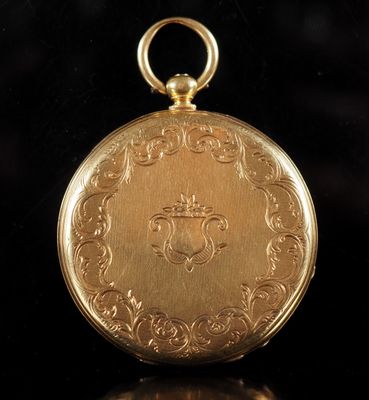an antique gold pocket watch with a chain on a black background