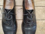 une paire de chaussures en cuir noir à lacets posée sur un parquet