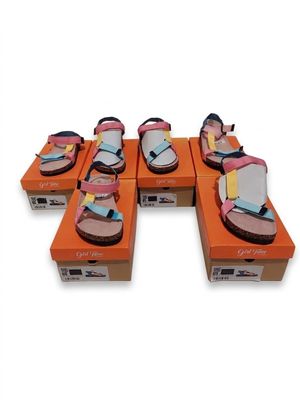 Plusieurs paires de sandales sont posées sur des cartons orange.