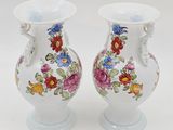 two vases with flowers painted on them sitting on a table