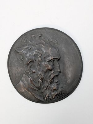 un vieux médaillon en bronze sur lequel est représenté le visage d'un homme