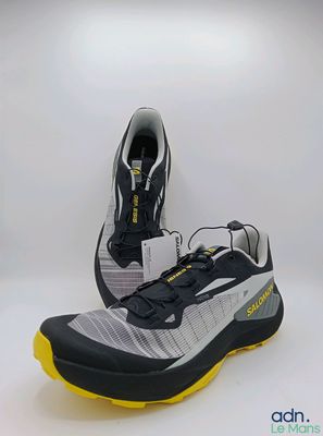 une paire de chaussures de course noires et jaunes sur fond blanc