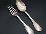 two silver spoons and a fork on a black surface