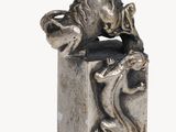 statue of a lion on a block with a snake in its mouth