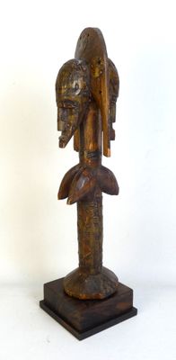 statue en bois représentant une femme avec un oiseau sur la tête, posée sur un socle
