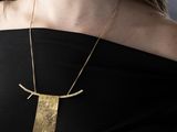 the woman is wearing a black dress and a gold necklace