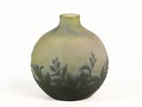 a green and black vase sitting on a white surface