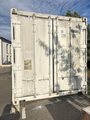 un grand conteneur blanc posé au bord de la route
