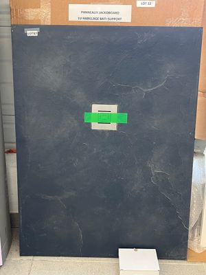 un réfrigérateur noir sur lequel est collé un autocollant vert, dans un entrepôt