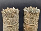 pair of antique brass vases with leaves on them on a black background