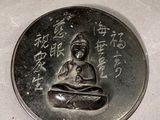 a silver coin with a picture of a buddha on it