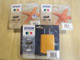 three epson ink cartridges are sitting on a table next to a starfish