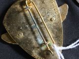 a gold brooch that has a pin on it