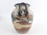 a vase with a handle on it that has a picture of a mountain scene on it