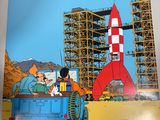 an image of a person holding up a book with a rocket in the background