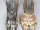 une paire de masques africains sur fond blanc avec un fond gris