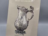 un vase ancien en argent exposé devant un fond gris
