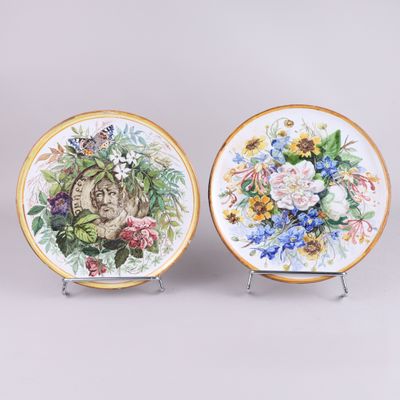 deux assiettes ornées de fleurs et d'un chat, posées sur un présentoir