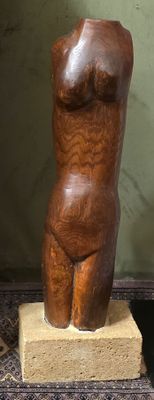 une sculpture en bois représentant un torse féminin posé sur un bloc