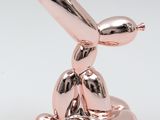 a pink balloon shaped like a dog with a baseball bat on it