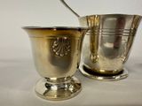 a silver cup with a spoon in it next to a silver cup with a spoon in it
