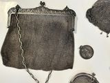 a silver purse sitting on top of a table next to other purses