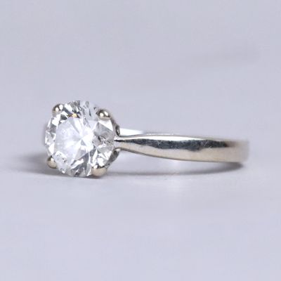un gros plan d'une bague sertie d'un seul diamant sur une surface blanche
