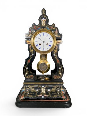 a black and gold clock on a stand on a white background
