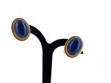 pair of gold and lapis stone earrings on a black stand